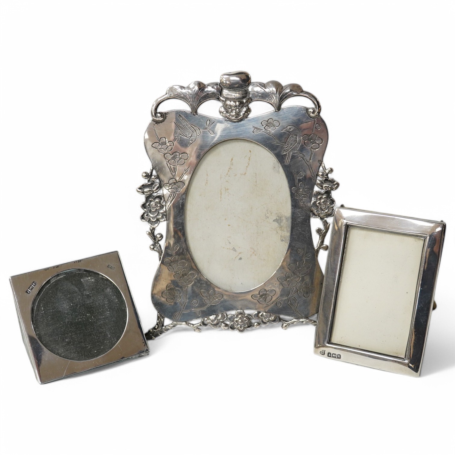 A Chinese Export engraved and embossed white metal photograph frame, maker KW, 14.5cm, together with two small Edwardian silver mounted photograph frames. Condition - fair to good